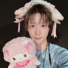 a person holding a stuffed animal and wearing a head piece with flowers on it's hair