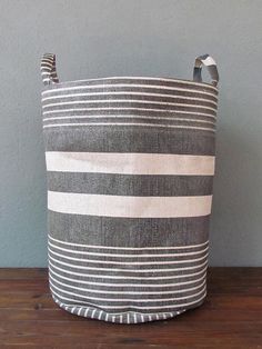 a black and white striped basket sitting on top of a wooden table next to a wall