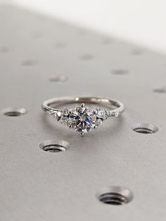 a three stone diamond ring sitting on top of a metal surface