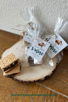 cookies and crackers wrapped in cellophane sitting on a wood slice with tags