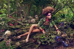 a woman sitting in the middle of a forest with lots of plants and flowers around her