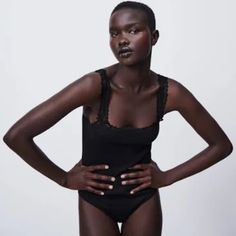 a woman in a black bodysuit with her hands on her hips