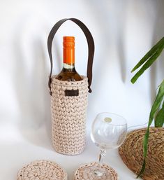 a wine bottle in a basket next to two coasters and a glass on a table