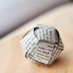 an origami ring made out of newspaper on top of a wooden table,