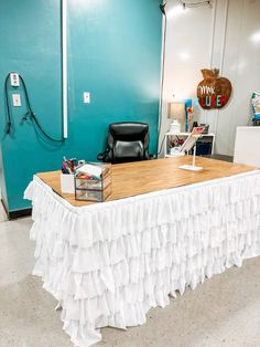 a table with a white ruffle skirt on it in front of a blue wall