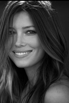 a black and white photo of a woman with long brown hair smiling at the camera