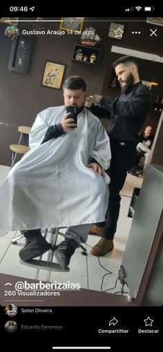 the man is getting his hair cut at the barbershop while another person looks on