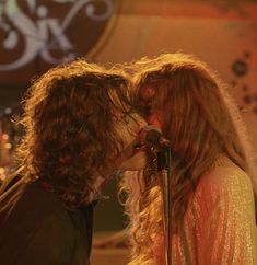 two people that are kissing in front of a microphone