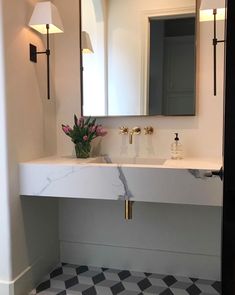 a bathroom with a checkered floor and marble counter top, along with a large mirror above the sink