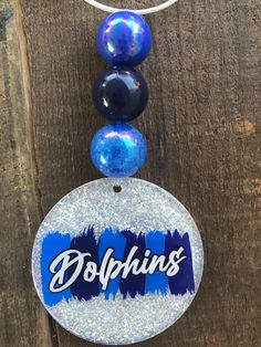 an ornament with the word dolphins hanging from it's side on a wooden surface