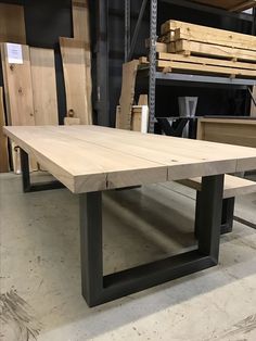 a wooden table with black metal legs in a warehouse