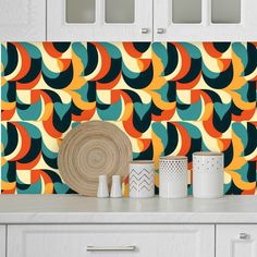 a kitchen with white cabinets and colorful wallpaper