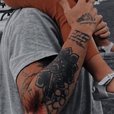 a man with a tattoo on his arm holding onto another person's shoulder at a baseball game