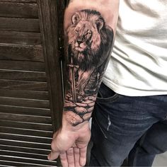 a man's arm with a lion tattoo on it and a cross in the middle