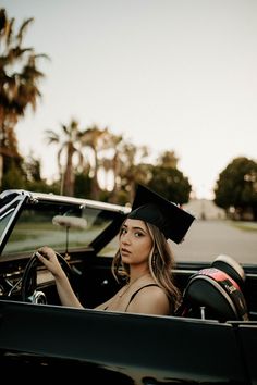 a woman sitting in the driver's seat of a convertible car wearing a graduation cap and gown