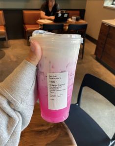 a person holding up a plastic cup with pink liquid