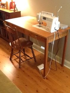 a sewing machine sitting on top of a wooden table next to a chair and lamp