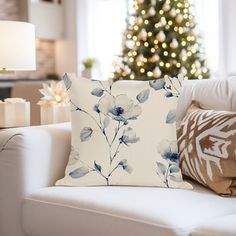 a living room with a christmas tree in the background and pillows on the couches