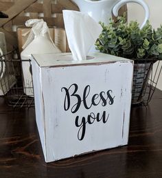 a wooden box that says,'bless you'with a tissue dispenser in the background