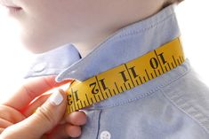 a close up of a person holding a measuring tape on their neck and wearing a blue shirt