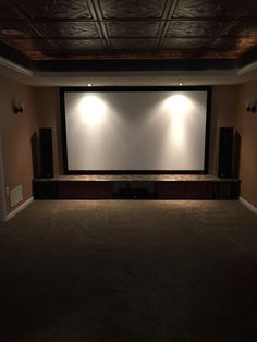 an empty room with two speakers and a projector screen in the middle of it