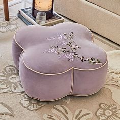 a purple foot stool sitting on top of a rug next to a clock and lamp