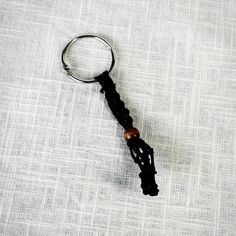 a keychain with a wooden bead hanging from it's side on a white cloth