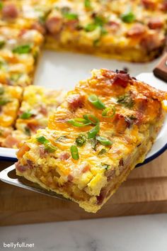 a slice of quiche is being held by a spatula on a cutting board