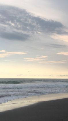 two people walking on the beach with their surfboards in hand and one person holding a surfboard