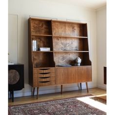 a wooden bookcase with two drawers and a cat sitting on it's top shelf