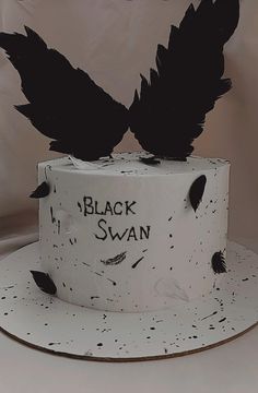 a white cake with black leaves on top and writing on the side that says, black swan