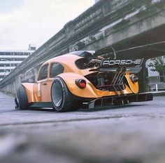 an orange race car parked in front of a bridge