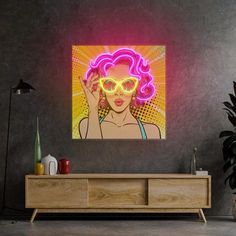 a woman with pink hair and yellow glasses in front of a neon light painting on the wall