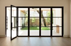 an empty room with sliding glass doors leading to a backyard area and trees in the background