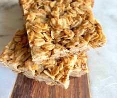 three granola bars stacked on top of each other next to a wooden cutting board