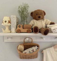 a teddy bear sitting on top of a white shelf next to a basket and lamp