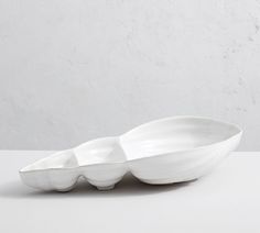 two white bowls sitting on top of each other in front of a white wall and floor