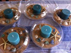 four clear dishes with candles and seashells in them