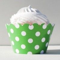 a cupcake with white frosting and green polka dot paper wrapper on top