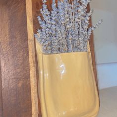 a yellow vase filled with lavender flowers on top of a counter