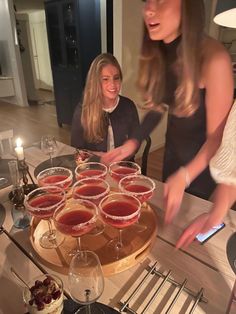 two women standing at a table with wine glasses and desserts in front of them