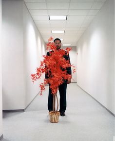 a man standing in a hallway holding a basket full of red leaves