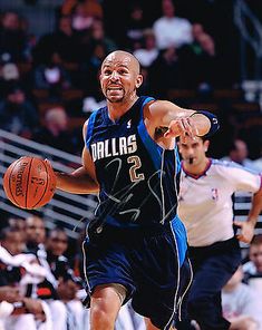 a basketball player dribbles the ball while being guarded by an opposing team member