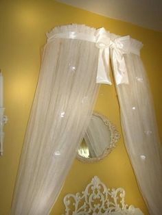 a white bed sitting under a window next to a mirror on top of a wall