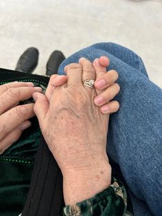 an older woman is holding her hand on the lap of another person's lap