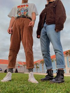 two young men standing next to each other in the grass