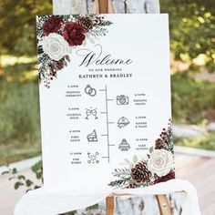 a welcome sign with flowers and pine cones on it for an outdoor wedding in the woods