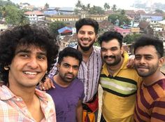 four men posing for the camera in front of a city