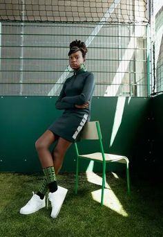 a woman sitting on top of a chair in front of a soccer goal with her arms crossed