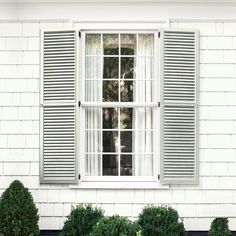 an open window with green shutters in front of a white house